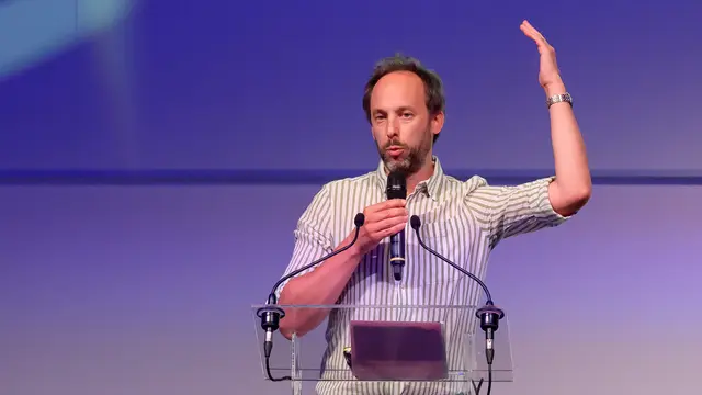 Daniel Dumont, professeur à l’ULB, au pupitre, le bras levé.